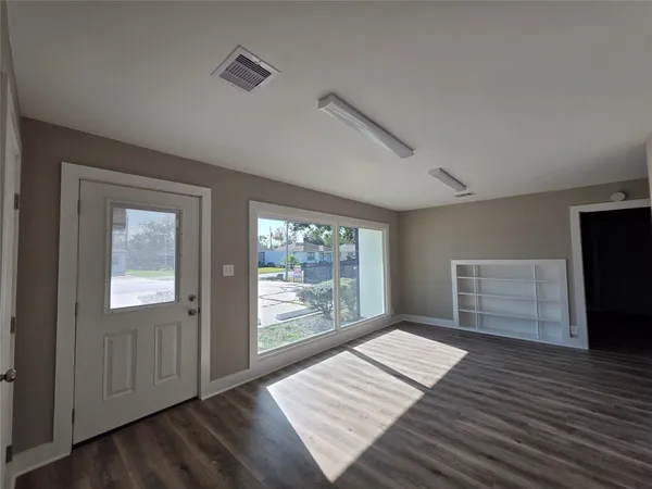an empty room with wooden floor cabinet and windows