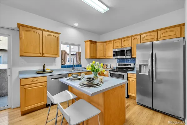 a kitchen with stainless steel appliances granite countertop a sink a stove a refrigerator cabinets and a dining table with wooden floor