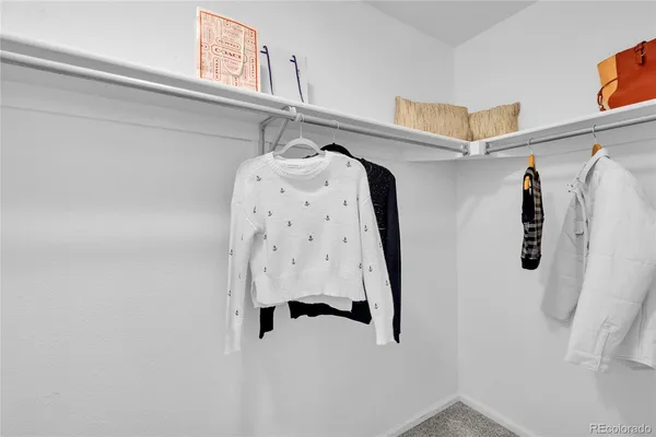 a view of walk in closet with clothes and shoes
