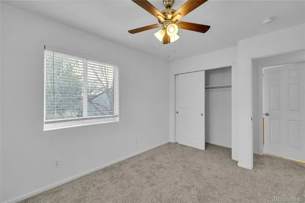 an empty room with windows and fan