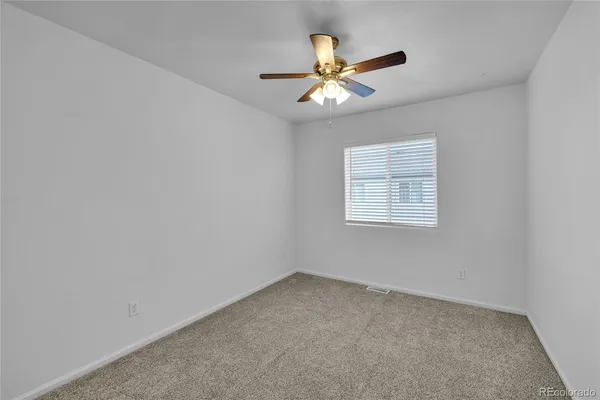 an empty room with a window and a fan
