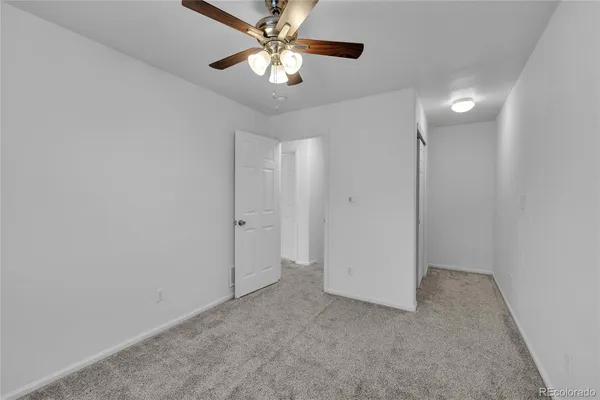an empty room with closet and a chandelier fan