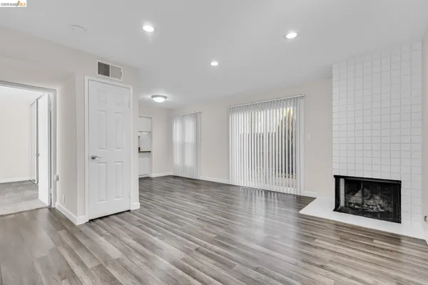 a view of an empty room with wooden floor fireplace and a window