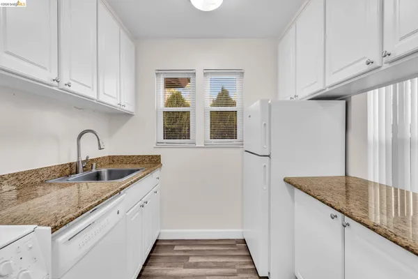 a kitchen with granite countertop a sink and white cabinets