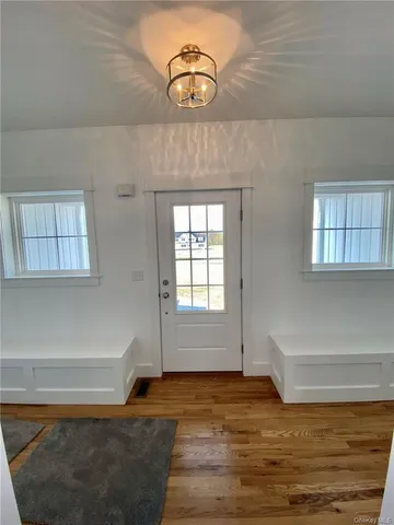 an empty room with wooden floor fireplace and windows
