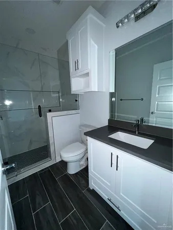 a bathroom with a granite countertop toilet sink and mirror