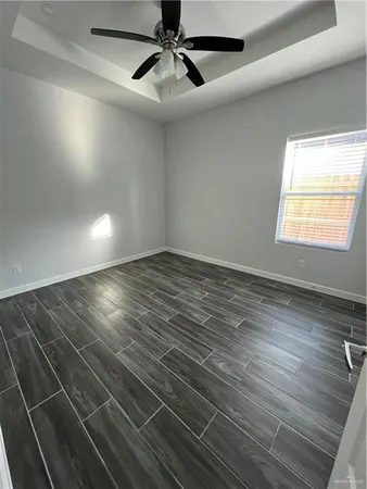 an empty room with wooden floor fan and windows