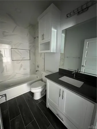 a bathroom with a granite countertop sink a toilet and bathtub