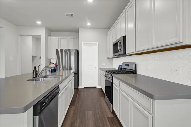 a kitchen with kitchen island granite countertop stainless steel appliances a sink stove top oven and refrigerator