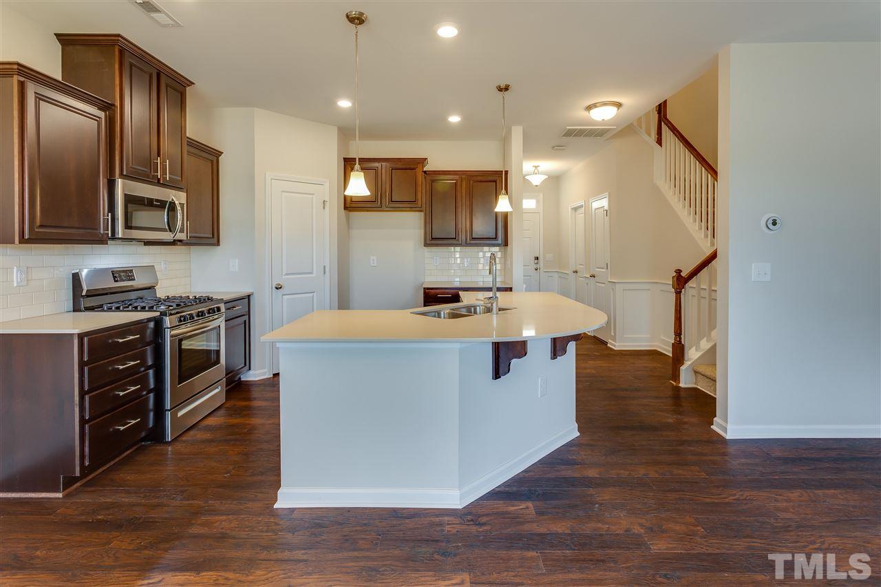 6004 Beale Loop, Unit 125 ABBEY Raleigh, NC 27616 - Photo 3 of 16 a large kitchen with stainless steel appliances kitchen island granite countertop a large counter top and stove top oven