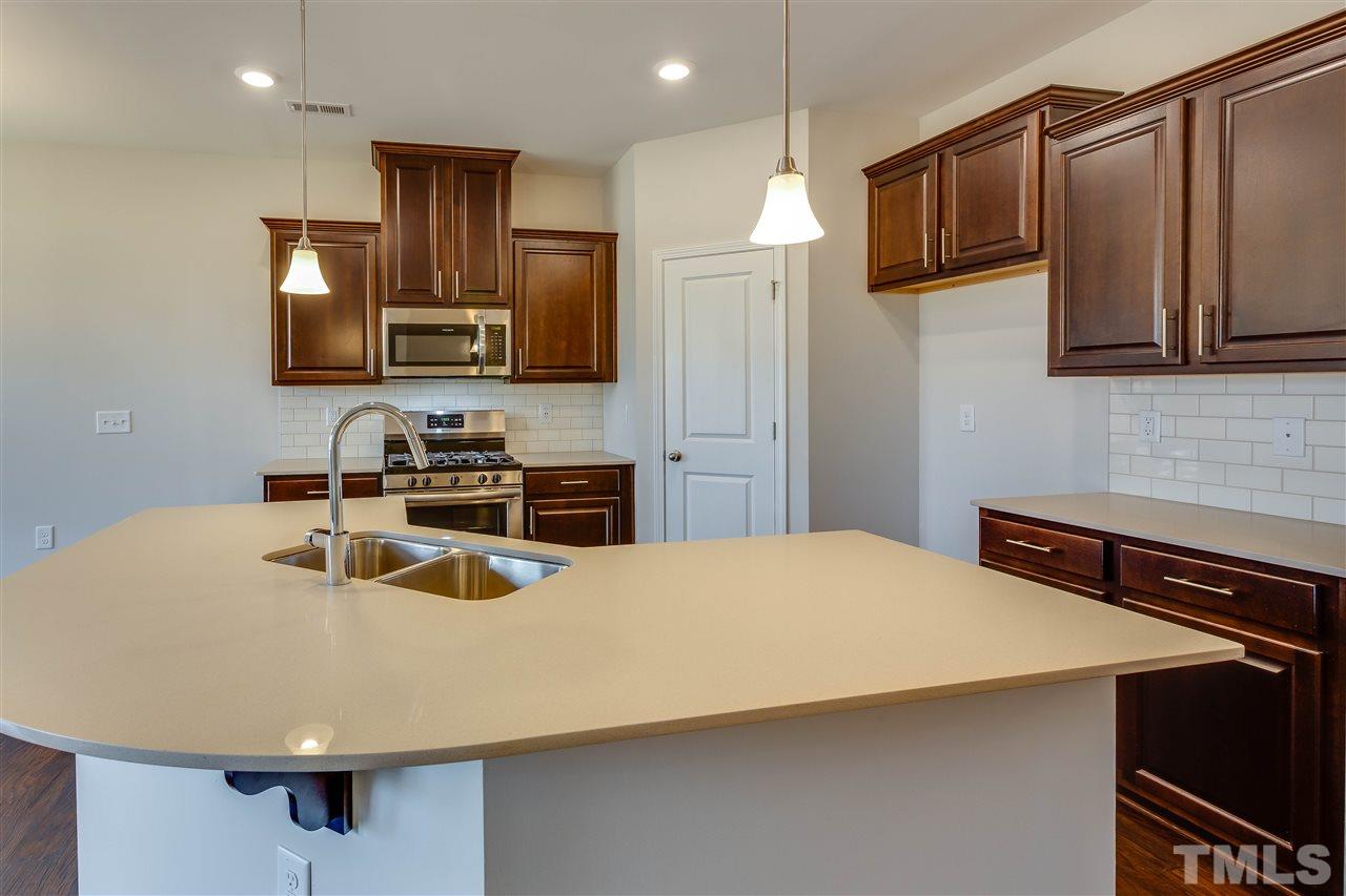 6004 Beale Loop, Unit 125 ABBEY Raleigh, NC 27616 - Photo 5 of 16 a kitchen with kitchen island white cabinets and stainless steel appliances
