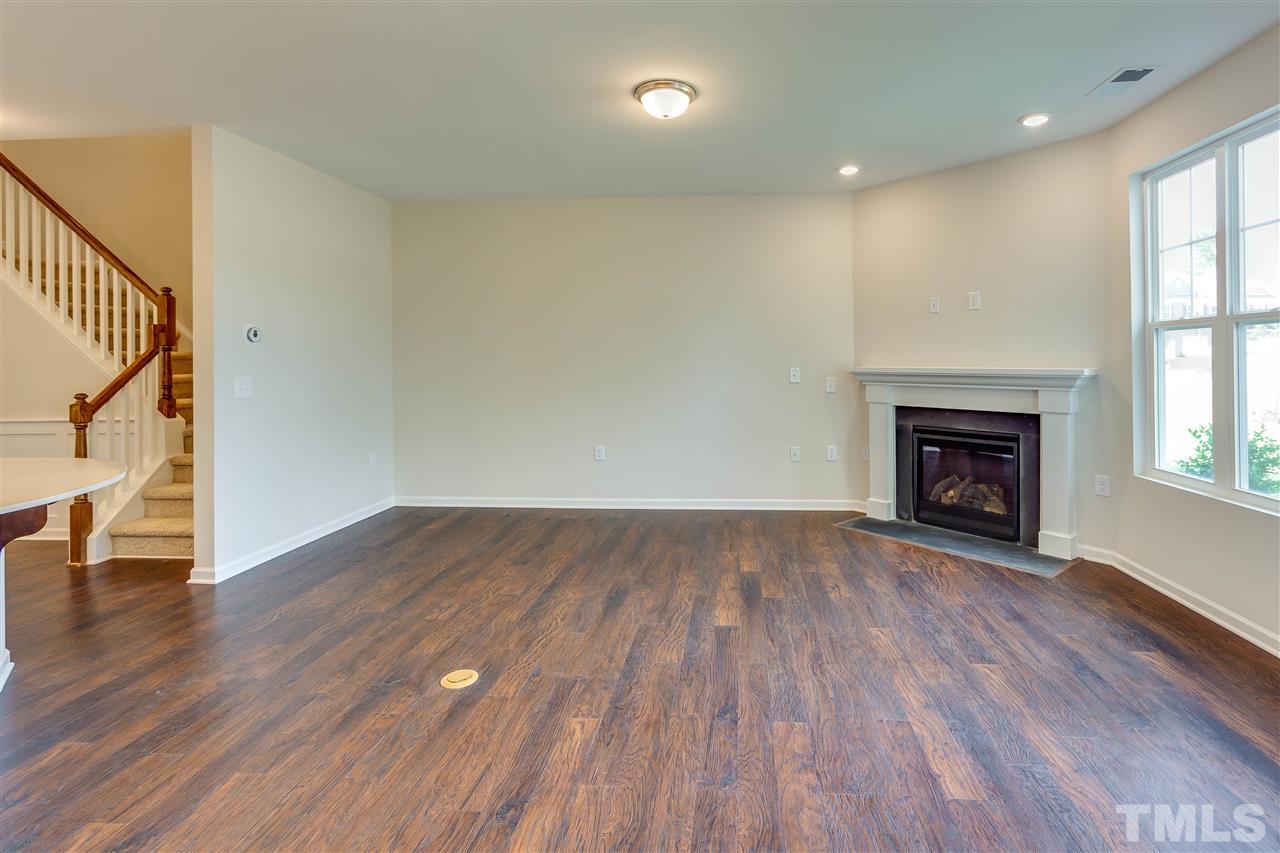 6004 Beale Loop, Unit 125 ABBEY Raleigh, NC 27616 - Photo 6 of 16 an empty room with wooden floor fireplace and windows