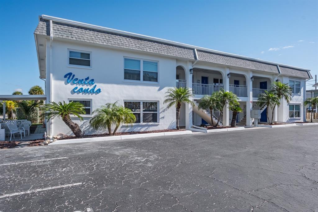 7151 Sunset Way, Unit 10 St. Pete Beach, FL 33706 - Photo 1 of 33 a view of a house with potted plants and a car parked in front of it
