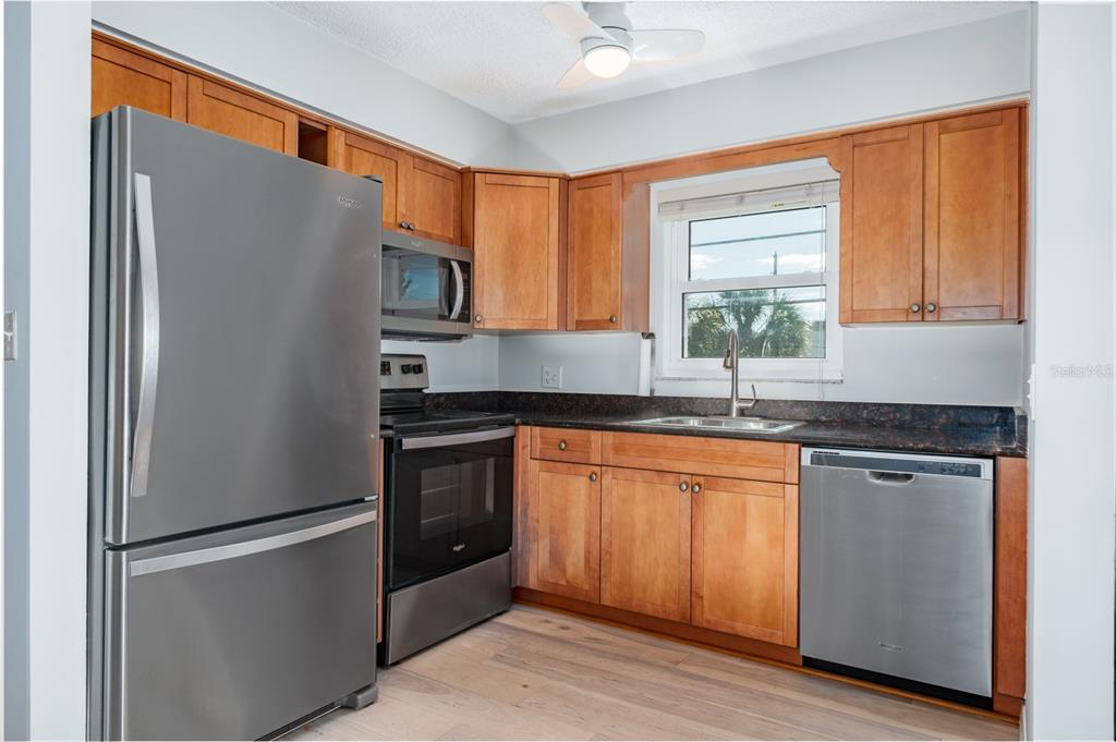 7151 Sunset Way, Unit 10 St. Pete Beach, FL 33706 - Photo 17 of 33 a kitchen with stainless steel appliances granite countertop a refrigerator and a sink