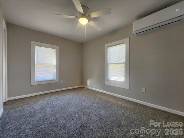an empty room with windows and fan