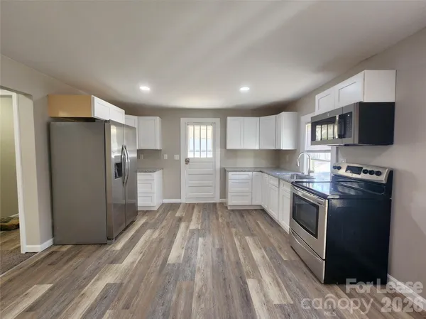 a kitchen with stainless steel appliances granite countertop a refrigerator oven a sink dishwasher and a stove with wooden floor