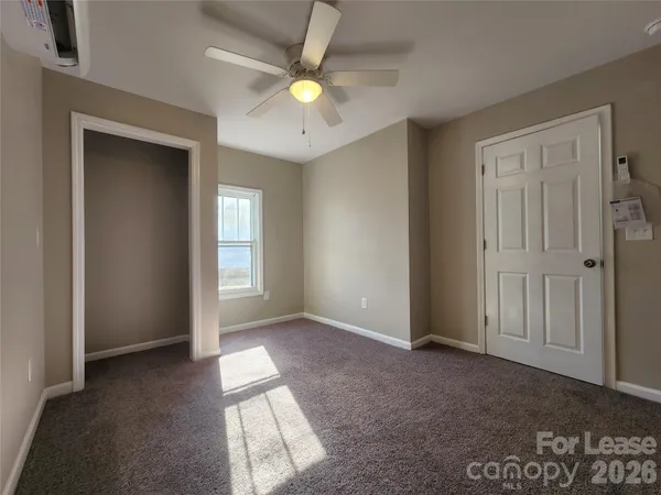 an empty room with windows and ceiling fan