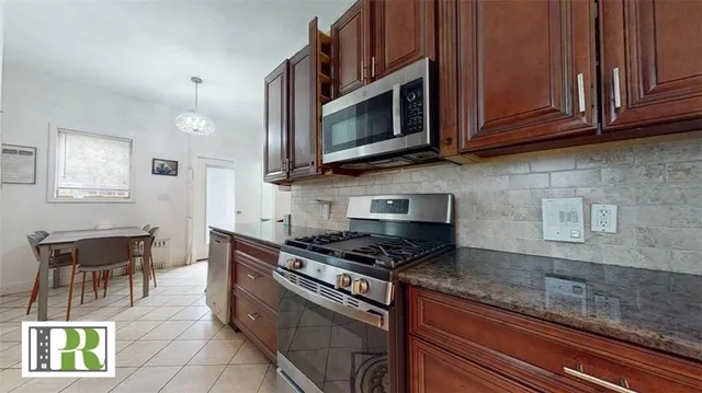 a kitchen with stainless steel appliances granite countertop a stove a microwave and wooden cabinets