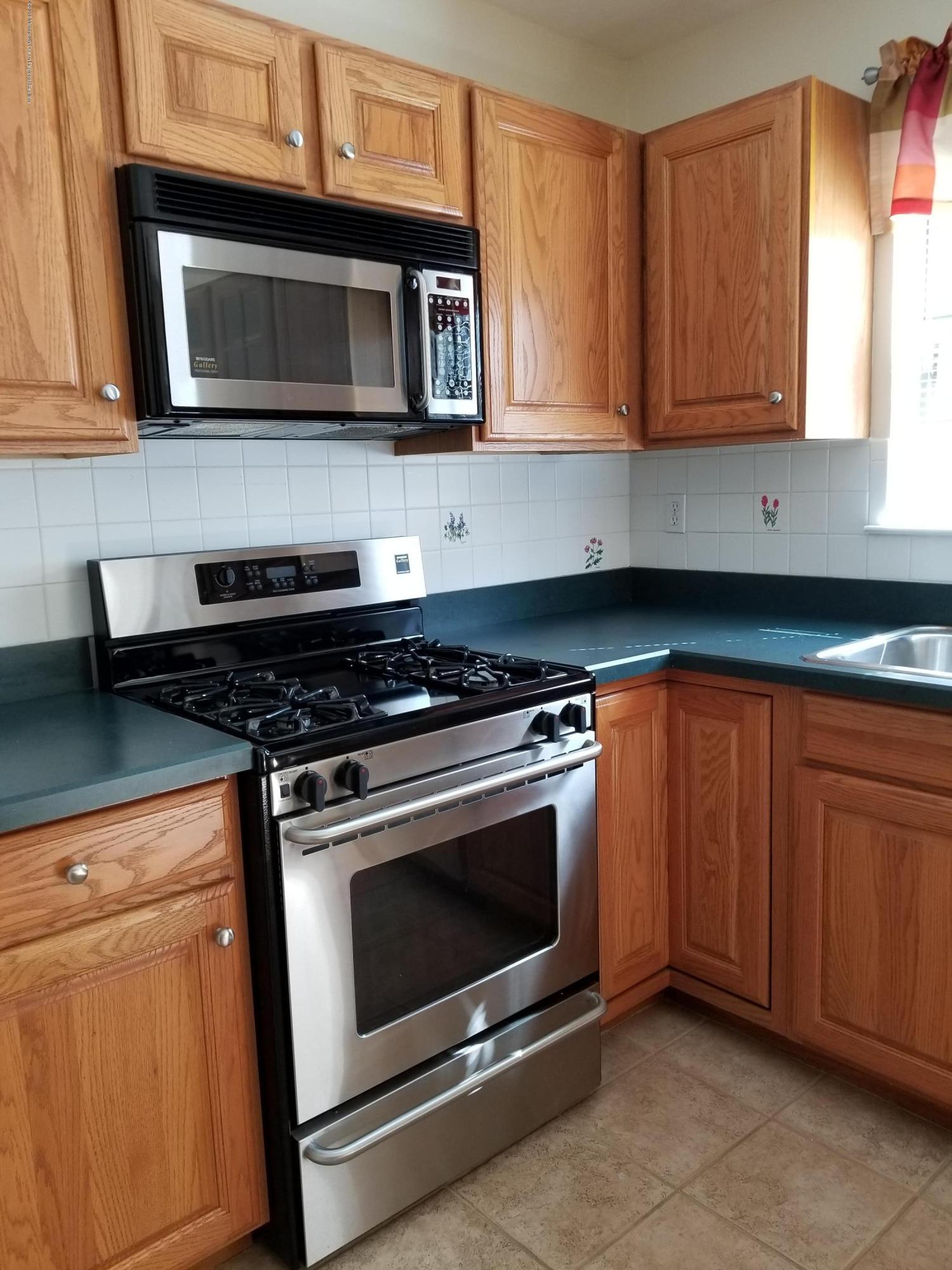 321 Spring Street, Unit 21 Red Bank, NJ 07701 - Photo 2 of 11 a kitchen with granite countertop wooden cabinets and stainless steel appliances