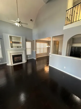 a view of a livingroom with furniture a fireplace wooden floor and windows