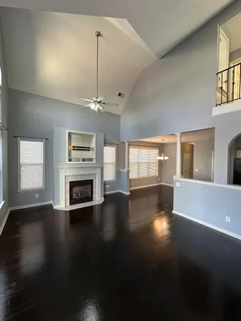 an empty room with wooden floor fireplace and windows