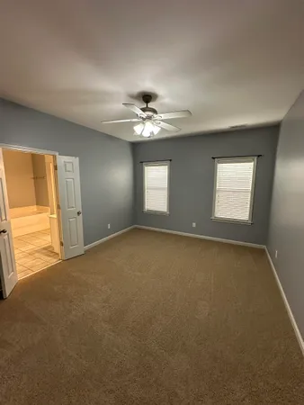 an empty room with windows and chandelier fan