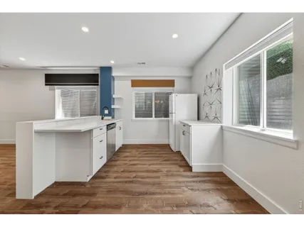 a view of entryway with kitchen and wooden floor