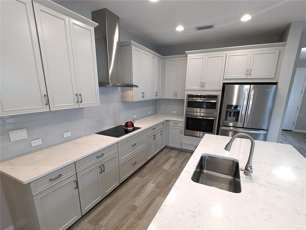 8545 Cache Drive Sarasota, FL 34240 - Photo 9 of 38 a kitchen with granite countertop a sink a refrigerator a stove and white cabinets