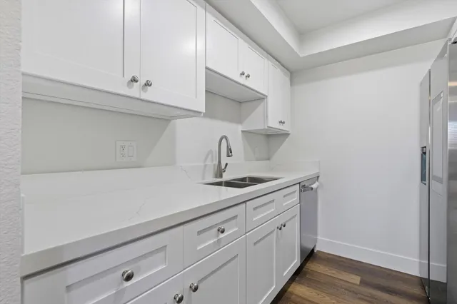 a kitchen with white cabinets and sink