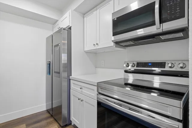 a kitchen with appliances cabinets and a wooden floor