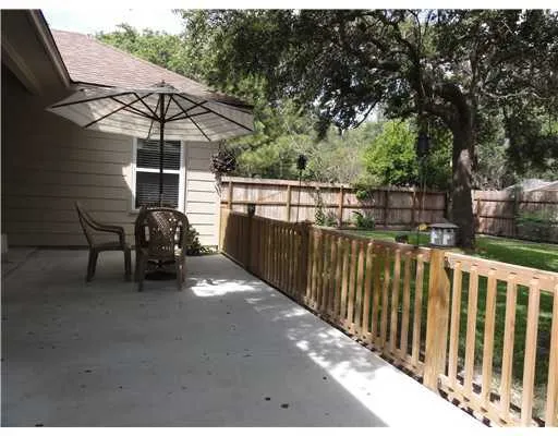 a view of a roof deck with table and chairs under an umbrella with wooden fence