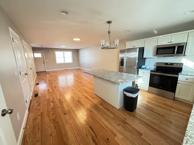a view of a kitchen with stainless steel appliances wooden floor and a window