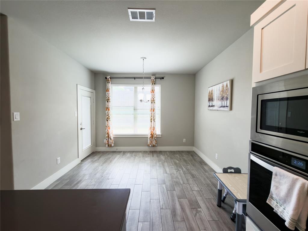 113 Nathan Drive Princeton, TX 75407 - Photo 10 of 40 an empty room with wooden floor fridge and windows