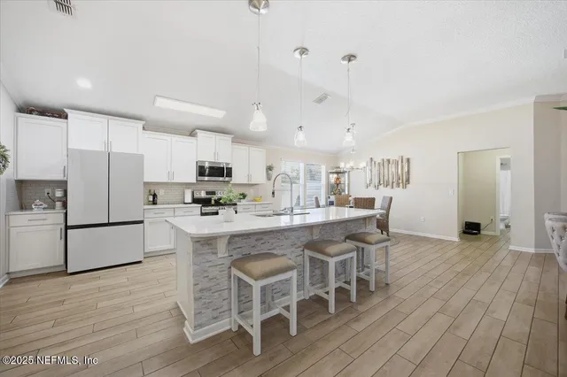 a kitchen with stainless steel appliances granite countertop a table chairs refrigerator and a stove top oven