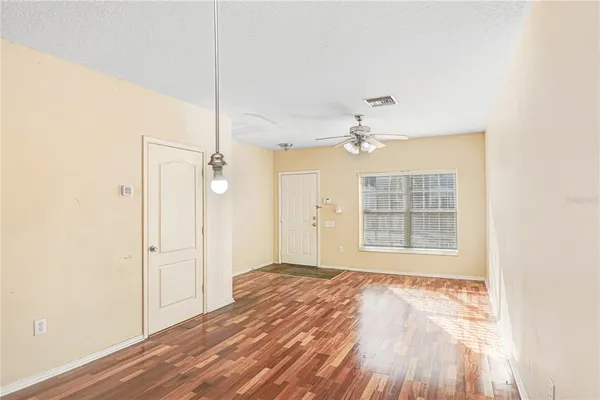 a view of an empty room with wooden floor and a window