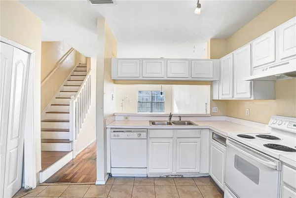 a kitchen with white cabinets appliances and a window