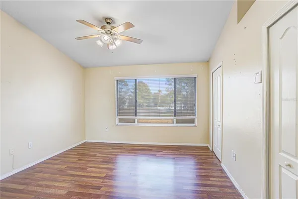 a view of an empty room with wooden floor and a window