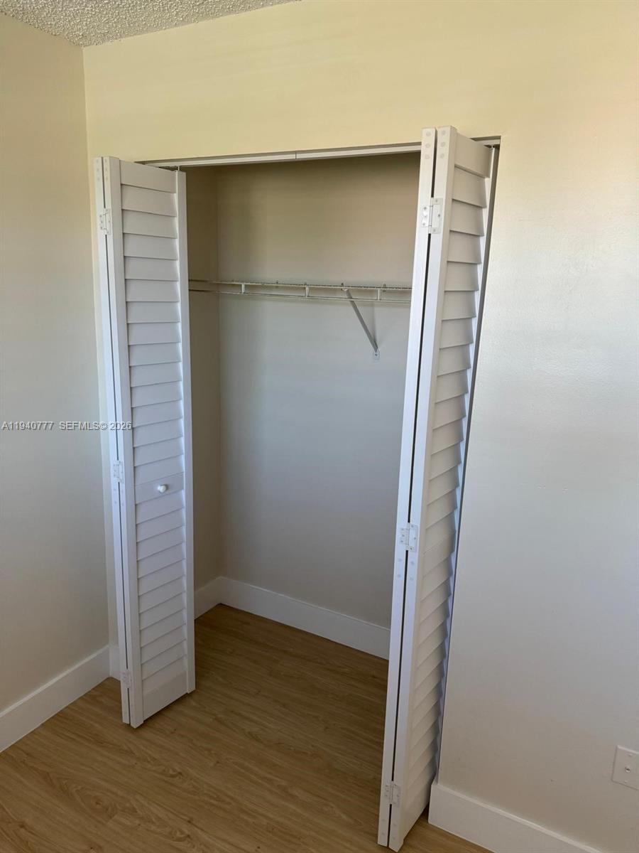 11307 Southwest 200th Street, Unit 310B Miami, FL 33157 - Photo 12 of 14 an empty room with wooden floor and cabinet
