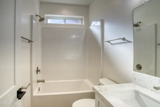 a bathroom with a granite countertop bathtub shower sink and toilet