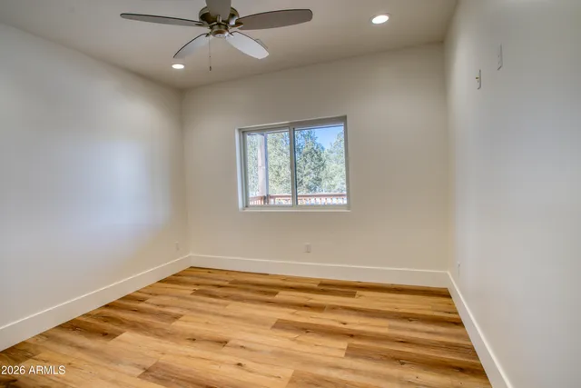 an empty room with a ceiling fan and window