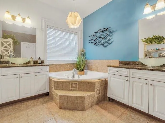 a spacious bathroom with a granite countertop sink a mirror and a bathtub