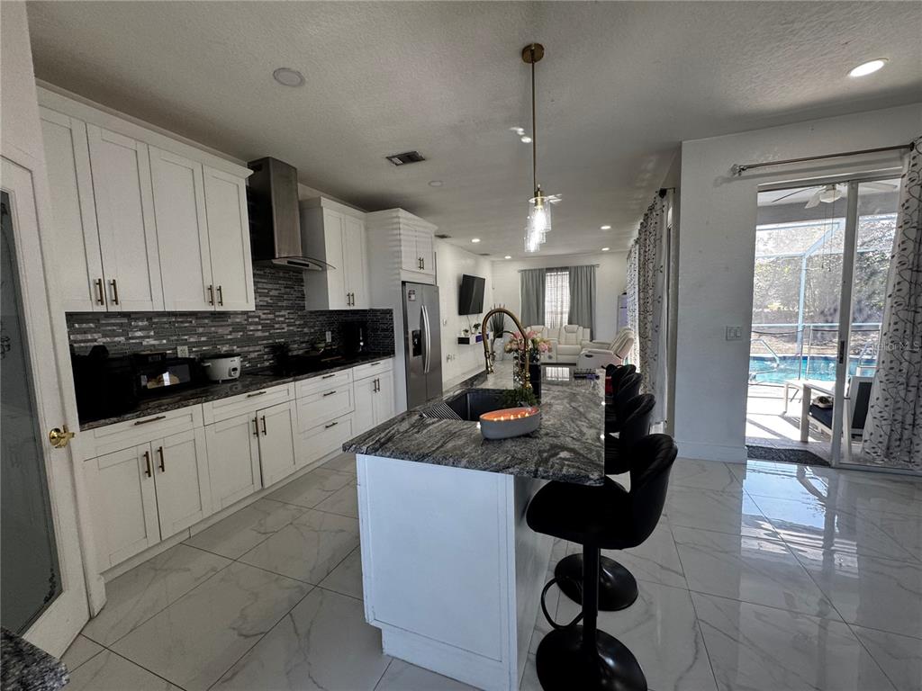 10130 Spring Hill Drive Spring Hill, FL 34608 - Photo 9 of 33 a kitchen with stainless steel appliances kitchen island granite countertop a sink dishwasher a stove a refrigerator and white cabinets with wooden floor