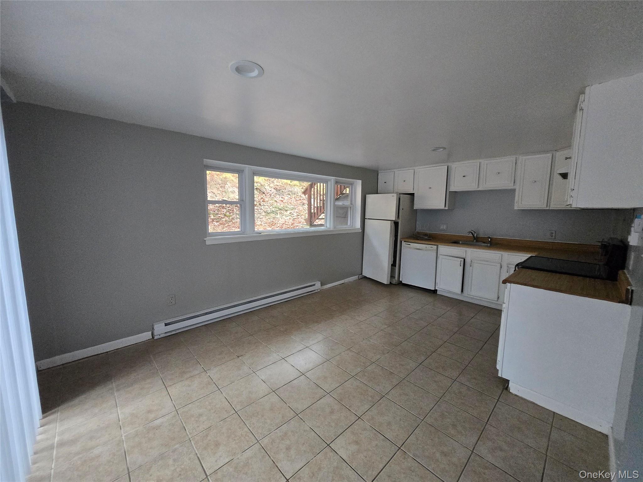 43 Glenmere Homesites Road Florida, NY 10921 - Photo 15 of 30 Kitchen featuring white cabinetry, baseboard heating, white appliances, and light tile patterned floors