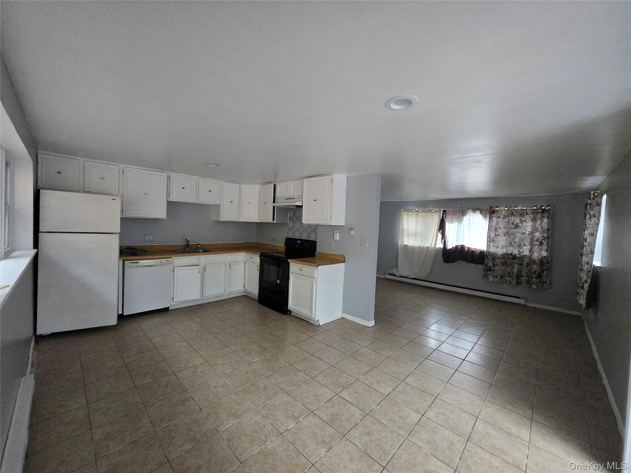 43 Glenmere Homesites Road Florida, NY 10921 - Photo 16 of 30 Kitchen with white appliances, white cabinetry, baseboard heating, light tile patterned floors, and under cabinet range hood