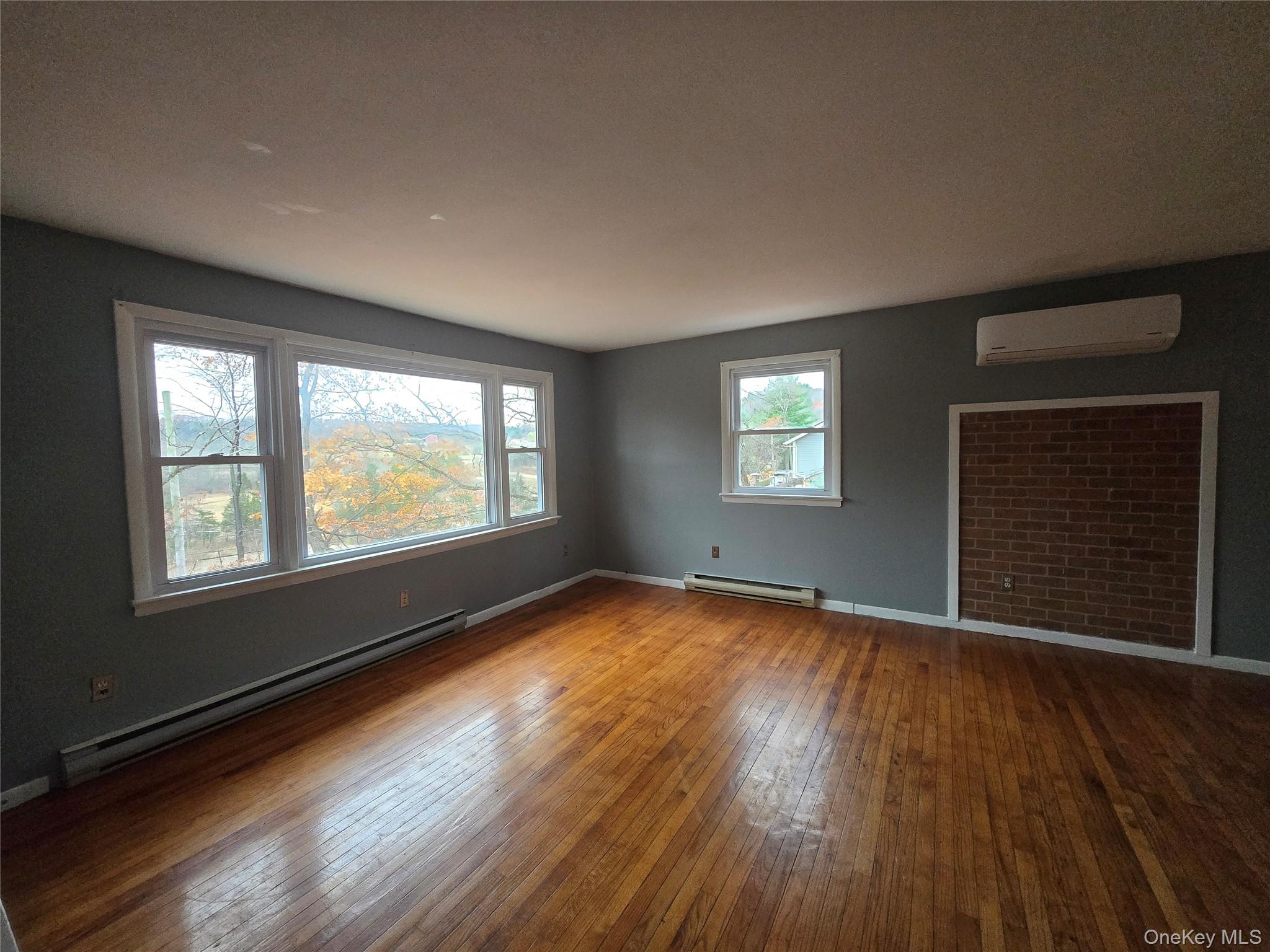 43 Glenmere Homesites Road Florida, NY 10921 - Photo 3 of 30 Spare room with baseboard heating, wood-type flooring, and a wall mounted AC