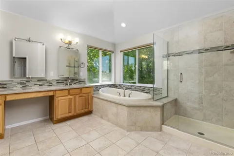 a bathroom with a tub a sink a mirror and a shower