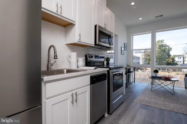 a kitchen with stainless steel appliances granite countertop a stove a sink and a microwave