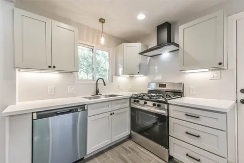 a kitchen with stainless steel appliances a sink stove and cabinets