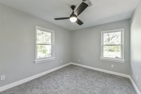 an empty room with a window and a fan