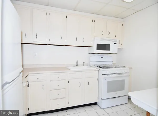 a kitchen with white cabinets and white appliances